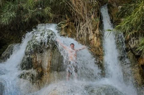 Young guy under the streams of a waterfall Stock Photos