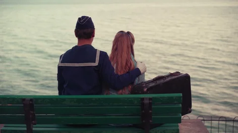 A young guy in uniform and a young girl are sitting on a bench Stock Footage 129847334