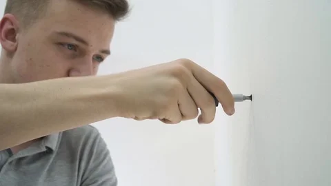 Young guy unscrews the screw with a screwdriver Stock Footage 107009062