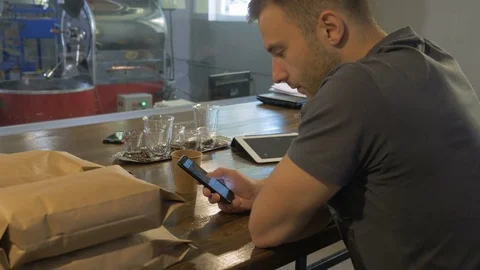 The young guy uses his smartphone in the coffee house. Stock Footage 82305904