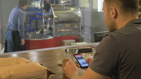 The young guy uses his smartphone in the coffee house. Stock Footage 82305906