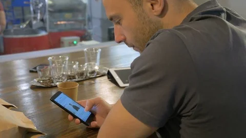 The young guy uses his smartphone in the coffee house. Stock Footage 82306061