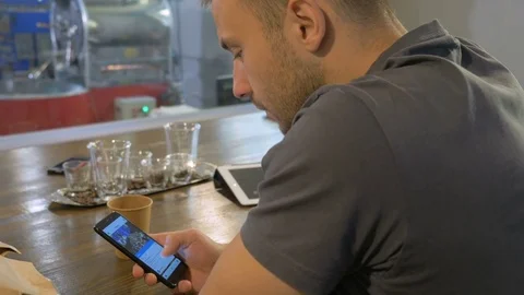 The young guy uses his smartphone in the coffee house. Stock Footage 82306149