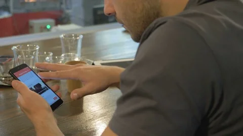 The young guy uses his smartphone in the coffee house. Stock Footage 82306657