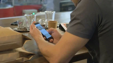 The young guy uses his smartphone in the coffee house. Stock Footage 82306968