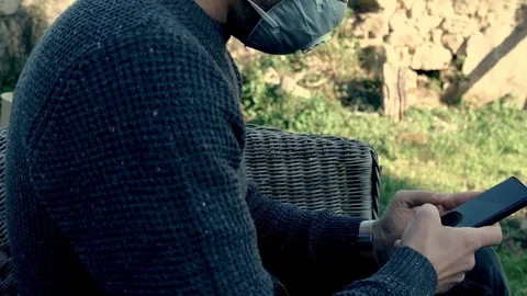 Young guy using android smartphone with safety mask in covid19 virus quarantine Stock Footage 126245013