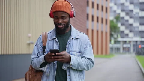 Young guy using device and looking with smile while standing on city street in Stock Footage 161745655