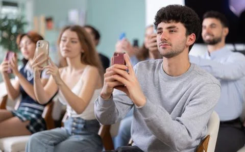 Young guy using mobile phone to scan QR code during interactive lesson Foto stock