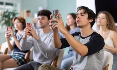 Young guy using mobile phone to scan QR code during interactive lesson Stock Photos