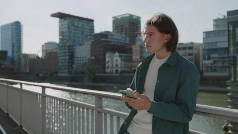 Young guy using modern smartphone standing on street Stock-Footage 166952117