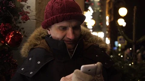 Young guy using smartphone on a urban street in evening standing near storefront Video stock 83917675