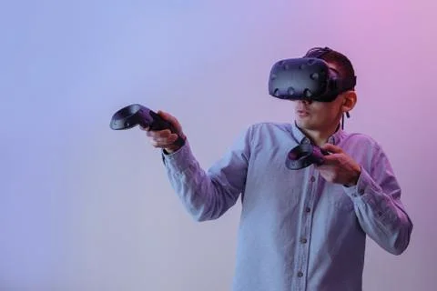 A young guy in virtual reality glasses plays video games. Stock Photos