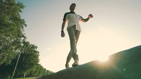 Young guy walking along the edge. Wearing casual clothes enjoys relaxing Stock Footage 97165225