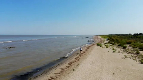 A young guy is walking along an empty beach near the sea Stock-Footage 158145341