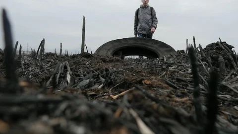 Young guy walking and stepping on the rubber tire on the burnt ground in the Видео 105545223