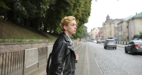 Young guy walking around the city. blond crosses the road. side view profile Stock Footage 126576063