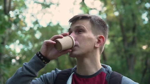 Young guy is walking in the park with a cup of coffee. sunset. close-up Video stock 208876291