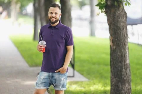 A young guy walking in the park with lemonade in the spring. Spring day. Stock Photos