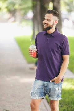 A young guy walking in the park with lemonade in the spring. Spring day. Stock Photos
