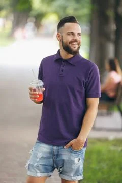 A young guy walking in the park with lemonade in the spring. Spring day. Stock Photos