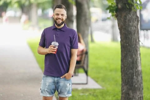 A young guy walking in the park with lemonade in the spring. Spring day. Stock Photos