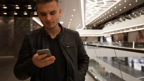 Young guy walking in a shopping mall, using smartphone. 库存影片 82170312