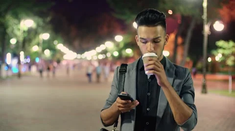 A young guy walking through the city after work, with coffee in hand, talking on Stock Footage