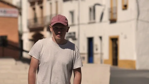 A young guy walks around the city, walks by, looks at the camera, leaves 스톡 동영상 121109155