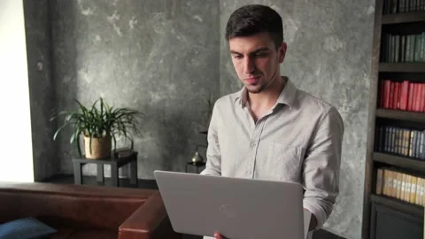 A young guy walks around the house with a laptop computer and gives instruct Stock Footage 198876755