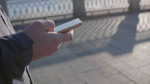 A young guy walks down the street and uses the phone for the Internet. Close-up. 库存影片 127522395