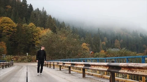 A young guy walks over the old bridge in the highlands of the Carpathians Video stock 96222962