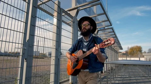 Young guy walks in the sunset light and plays the guitar. Freedom concept Stock Footage 119599721