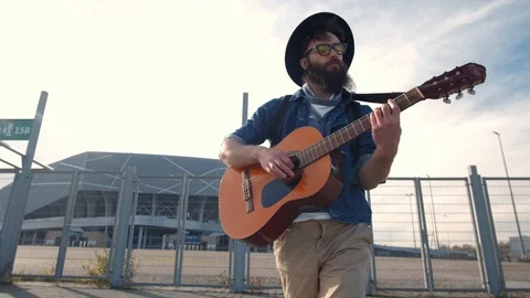 Young guy walks in the sunset light and plays the guitar. Freedom concept Stock Footage 119600019