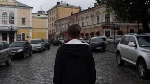 A young guy walks through the old town, turns his head to the side Stock Footage 127432370
