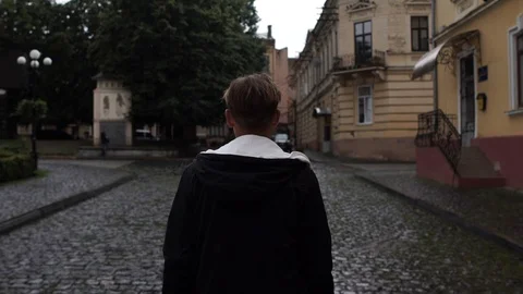 A young guy walks through the old town, turns his head to the side Stock Footage 127432673