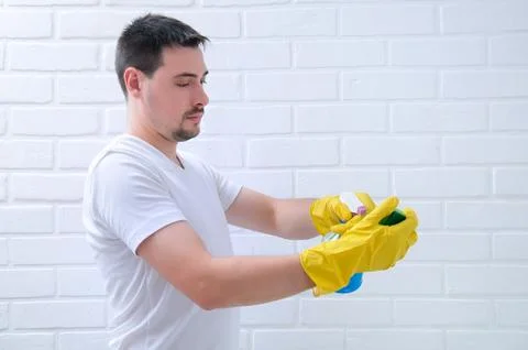 A young guy washes a brick, white wall. The guy cleans the house. Cleaning th Stock Photos