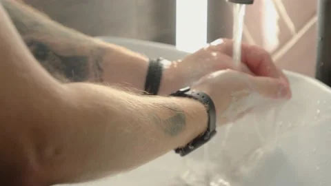 A young guy washes his hands with soap suds and then rinses with water. Stock Footage 138999065