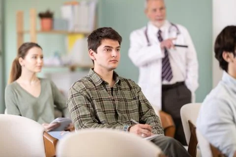Young guy watching presentation with a doctor standing in background Stock Photos