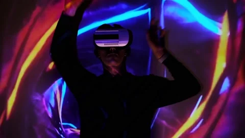 Young guy wave hands in front of display. Man watches and using VR-helmet virtua Stock Footage 130180215