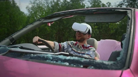 Young guy wearing white virtual reality headset is sitting in pink convertible Stock Footage 237042702