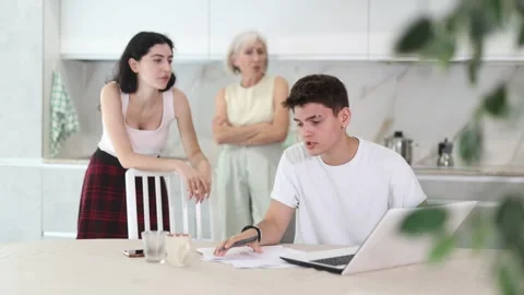Young guy while working on laptop listens to claims of elderly mother and young Stock Footage 331300673