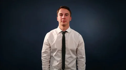 Young guy in a white shirt claps his hands on a dark blue background Stock Footage 72372445
