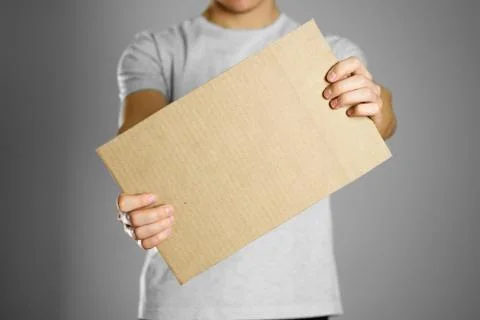 A young guy in a white t-shirt holding a piece of cardboard. Prepared for you Stock-Fotos