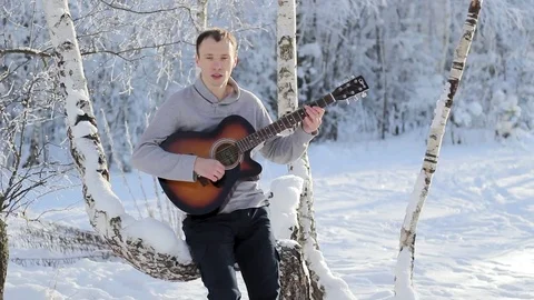 Young guy in the winter playing guitar Stock-Footage 85026359