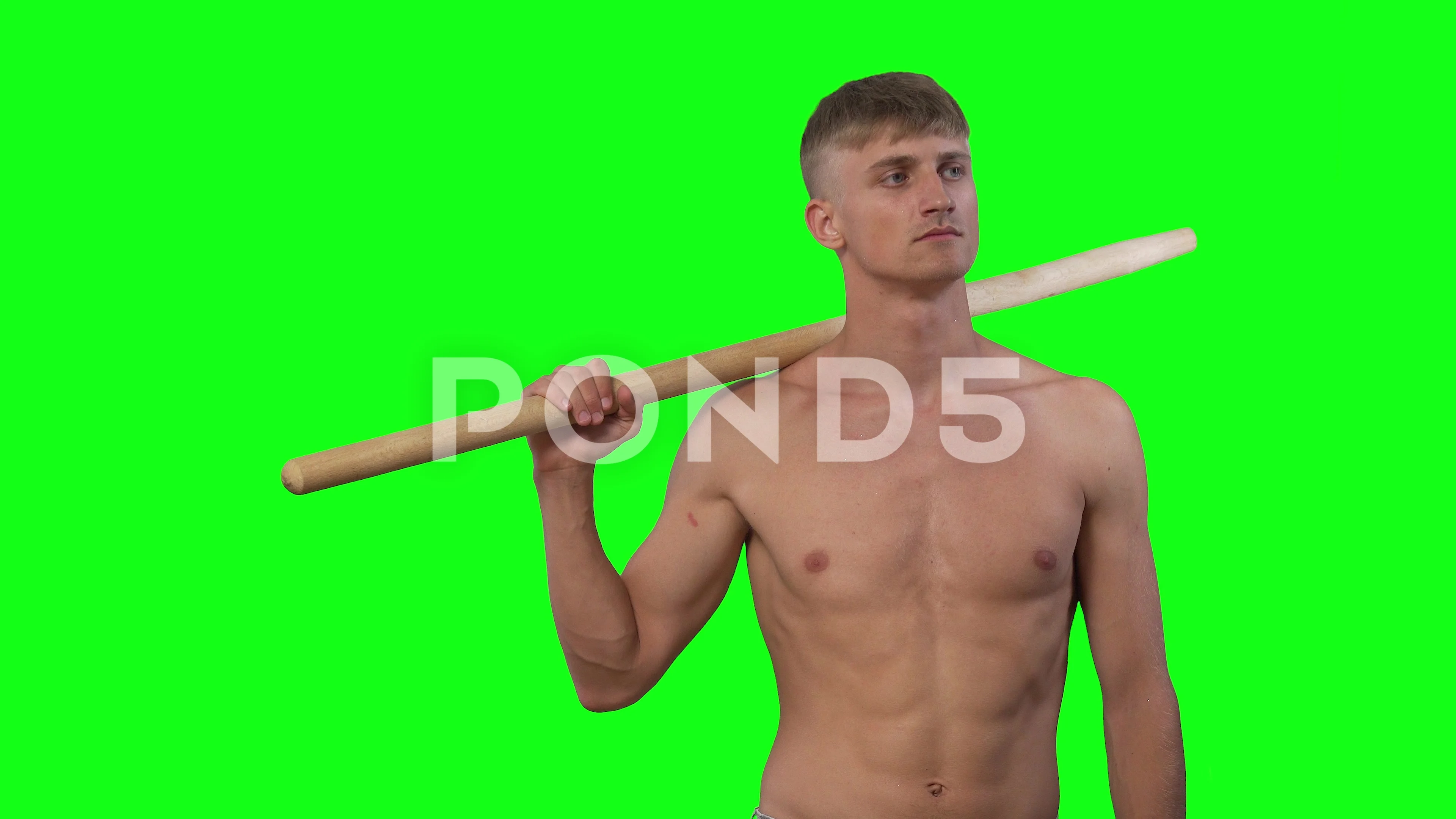 young guy without clothes holds stick in his hand and looks around green  screen