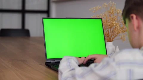 Young guy working on a computer with green screen layout, chromokey. Guy in cozy Stock Footage 272440234