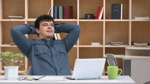 Young guy working at his laptop, leans back in chair, pleased with the result Stock Footage 63364357
