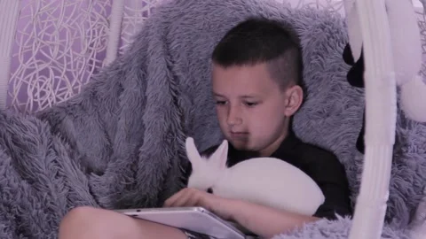 Young guy working on a tablet while sitting on an armchair bed Stock Footage 198726389