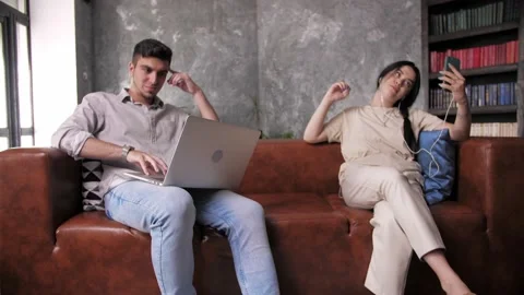 A young guy works remotely on his laptop while his girlfriend looks at her  Stock Footage 198876805