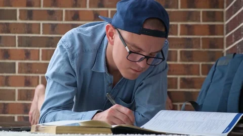 A young guy writes notes in a notebook lying on the floor Stock Footage 201615764